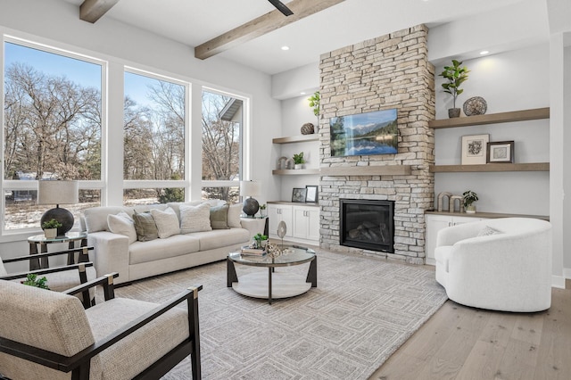 living room with beam ceiling, a fireplace, and light hardwood / wood-style flooring