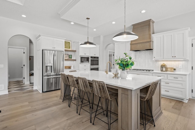 kitchen with a large island, stainless steel appliances, a kitchen breakfast bar, hanging light fixtures, and white cabinets