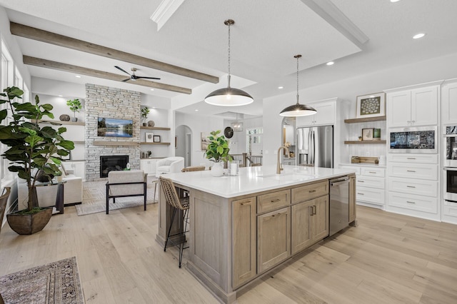 kitchen with white cabinetry, stainless steel appliances, beamed ceiling, hanging light fixtures, and a large island