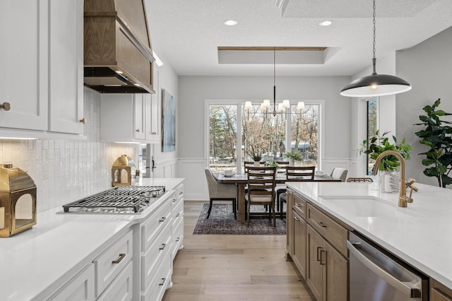 kitchen featuring decorative light fixtures, sink, white cabinetry, and stainless steel appliances