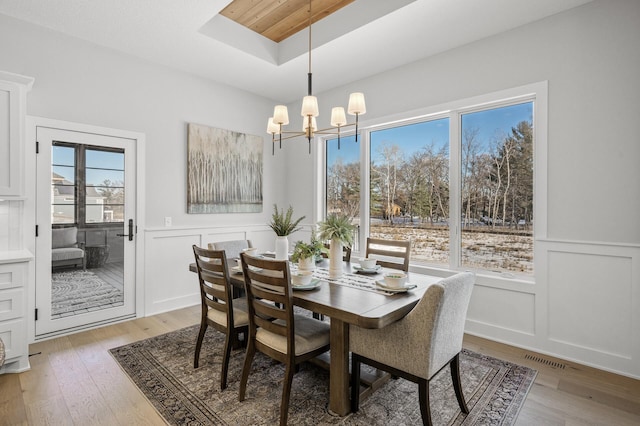 dining space with a tray ceiling, an inviting chandelier, and hardwood / wood-style floors