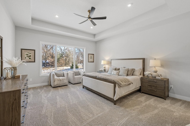 carpeted bedroom with ceiling fan and a raised ceiling