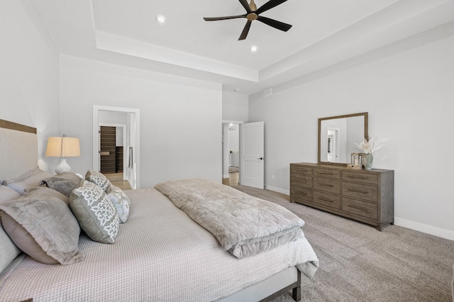 bedroom featuring ceiling fan, a tray ceiling, and light carpet