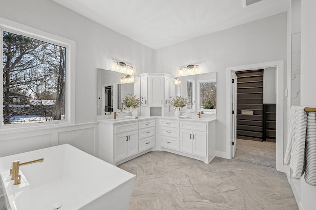 bathroom featuring a tub to relax in, vanity, and a healthy amount of sunlight