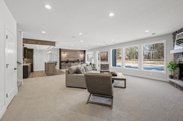 carpeted living room featuring a textured ceiling and a stone fireplace