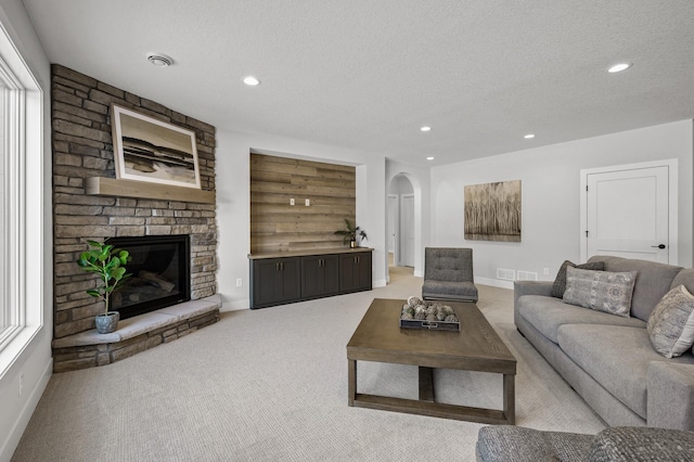 carpeted living room with a textured ceiling and a fireplace