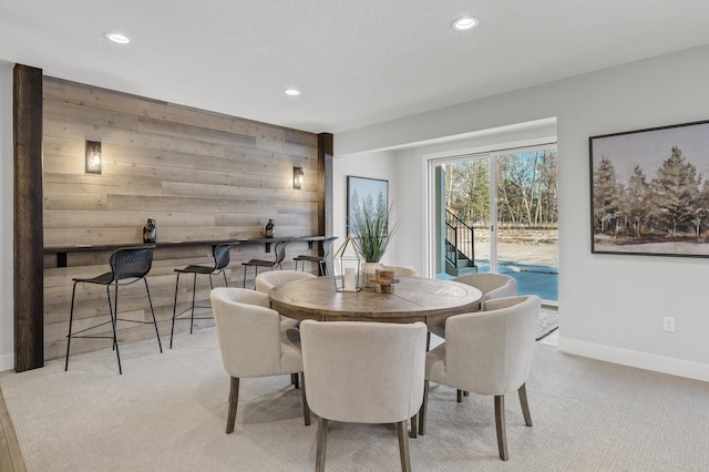 carpeted dining area featuring wood walls