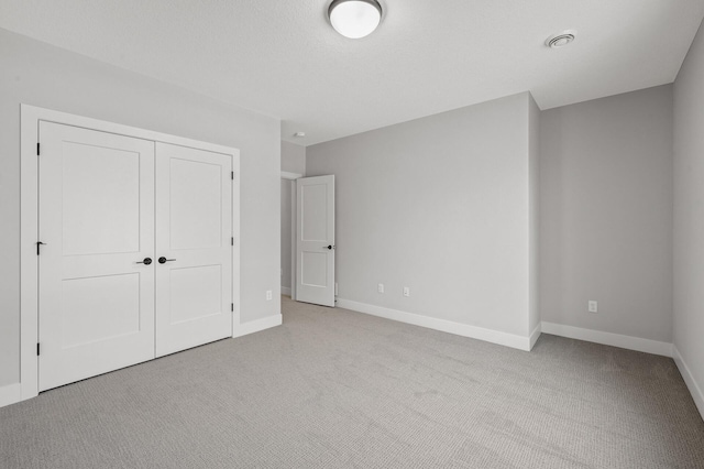 unfurnished bedroom with light colored carpet and a closet