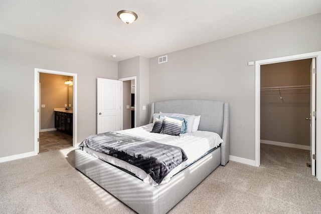 bedroom featuring a walk in closet, carpet, a closet, and ensuite bath