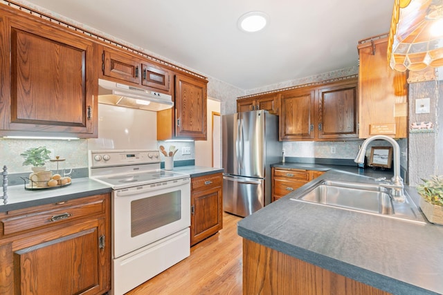 kitchen with electric stove, sink, stainless steel fridge, hanging light fixtures, and light hardwood / wood-style floors