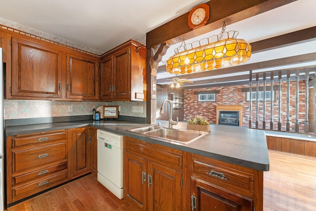 kitchen with sink, pendant lighting, white dishwasher, and kitchen peninsula