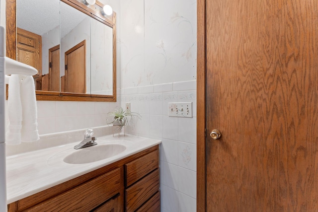 bathroom with vanity, a textured ceiling, and tile walls