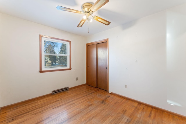 unfurnished bedroom featuring ceiling fan, light hardwood / wood-style floors, and a closet