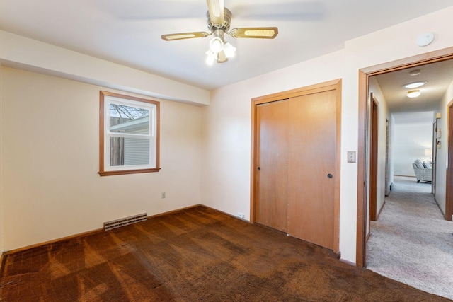 unfurnished bedroom featuring a closet, ceiling fan, and dark colored carpet