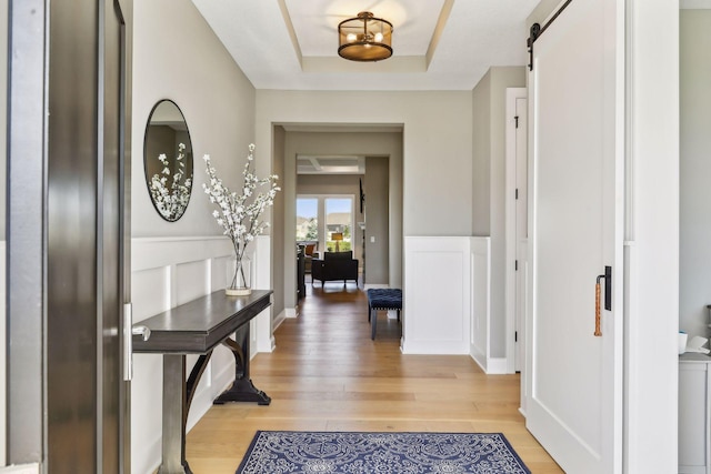 foyer entrance featuring hardwood / wood-style floors, a tray ceiling, and a barn door