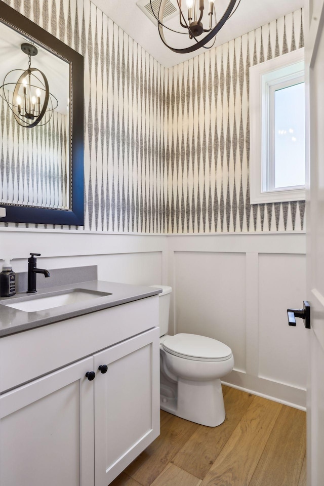 bathroom featuring wood-type flooring, toilet, a chandelier, and vanity