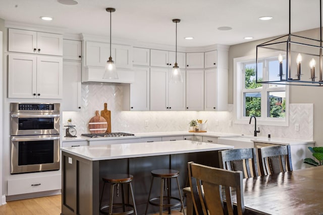 kitchen with a kitchen breakfast bar, appliances with stainless steel finishes, sink, white cabinets, and a center island