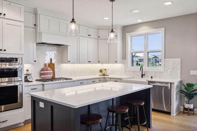 kitchen featuring pendant lighting, white cabinets, a center island, stainless steel appliances, and sink