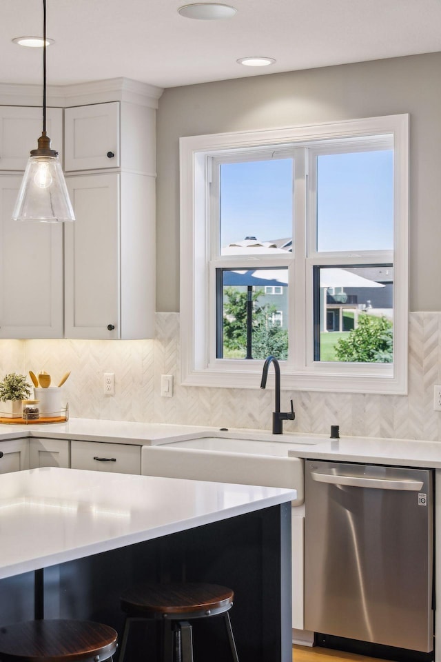 kitchen with pendant lighting, white cabinetry, tasteful backsplash, a kitchen breakfast bar, and stainless steel dishwasher