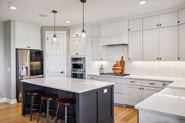 kitchen with white cabinets, stainless steel appliances, light hardwood / wood-style floors, and decorative backsplash