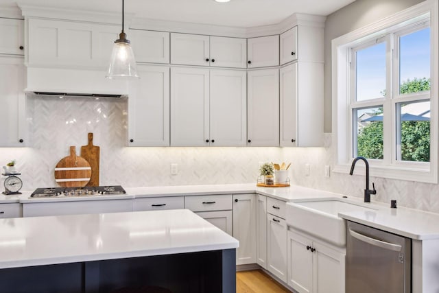 kitchen with sink, backsplash, white cabinets, and appliances with stainless steel finishes