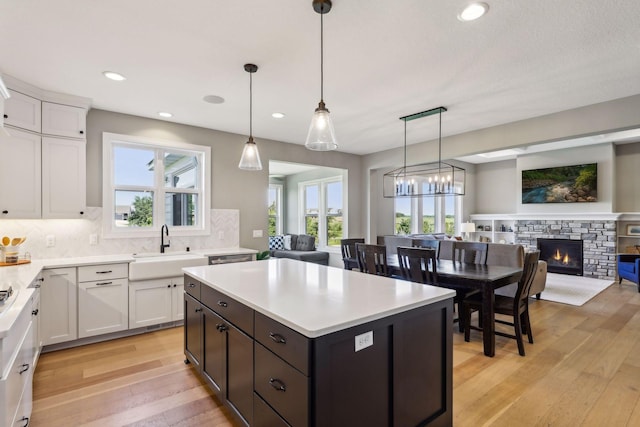 kitchen with pendant lighting, sink, light wood-type flooring, white cabinetry, and decorative backsplash