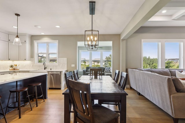 dining area with light hardwood / wood-style floors, sink, and a notable chandelier