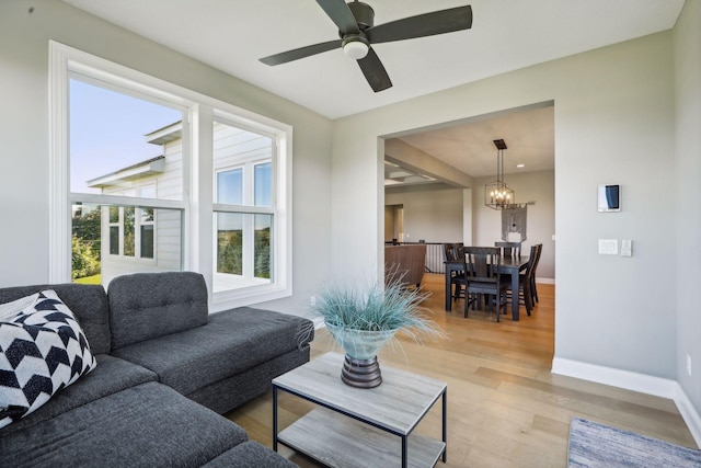 living room with hardwood / wood-style flooring and ceiling fan with notable chandelier