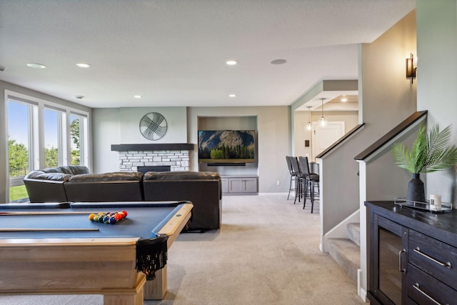 game room with billiards, a stone fireplace, and light colored carpet