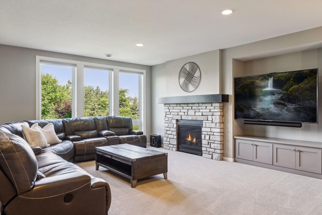 carpeted living room with plenty of natural light and a stone fireplace