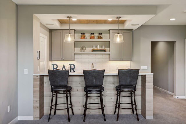 bar with pendant lighting, gray cabinetry, and a raised ceiling