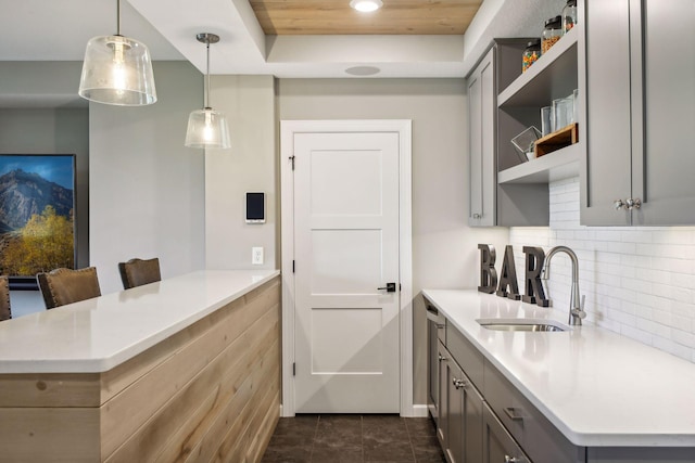 kitchen with sink, decorative light fixtures, gray cabinetry, and kitchen peninsula