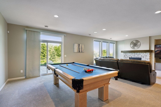 game room featuring a textured ceiling, light colored carpet, a fireplace, and pool table