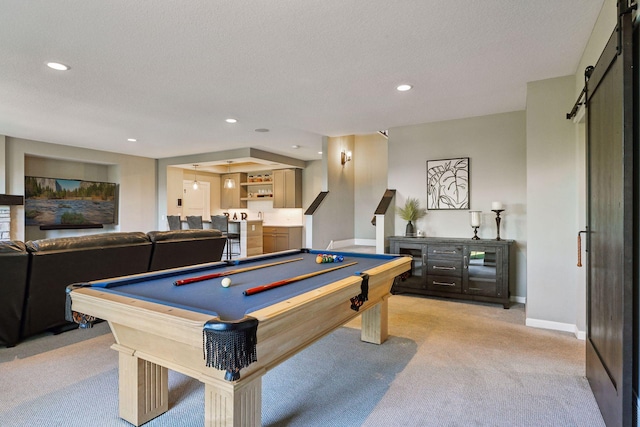 rec room with billiards, a barn door, a textured ceiling, and light carpet