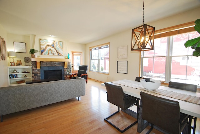 dining area with an inviting chandelier, a fireplace, and light wood-type flooring