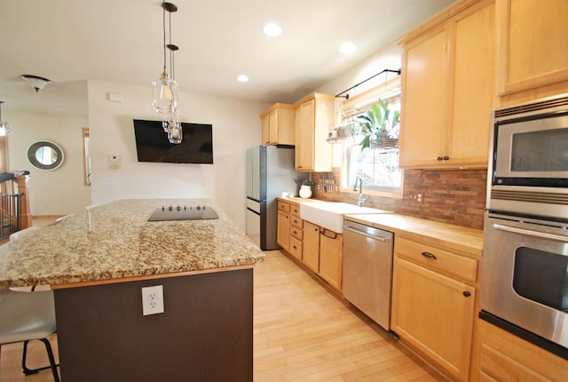 kitchen with a kitchen island, appliances with stainless steel finishes, light brown cabinetry, sink, and backsplash