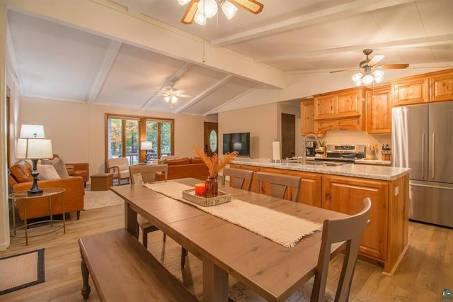 kitchen with appliances with stainless steel finishes, lofted ceiling with beams, and light wood-type flooring