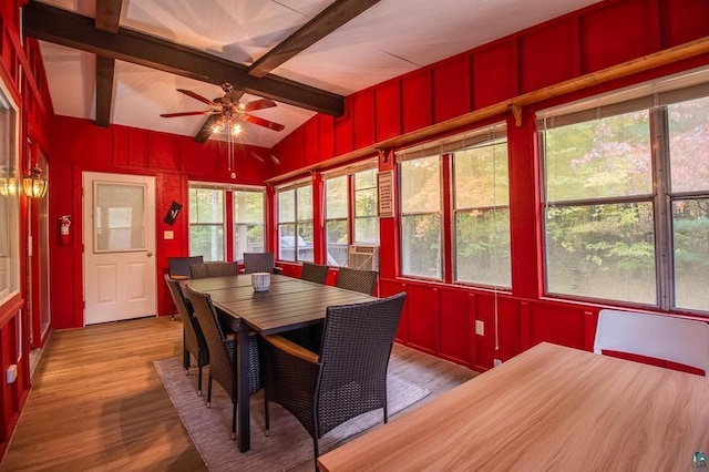 dining space with ceiling fan, vaulted ceiling with beams, and hardwood / wood-style floors