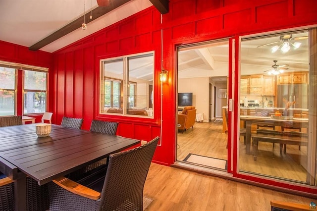 dining space with light hardwood / wood-style floors, vaulted ceiling with beams, and ceiling fan