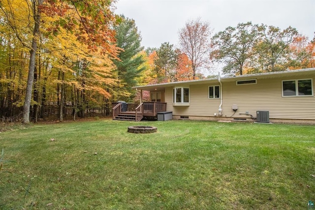 back of house featuring a wooden deck, an outdoor fire pit, a yard, and central AC