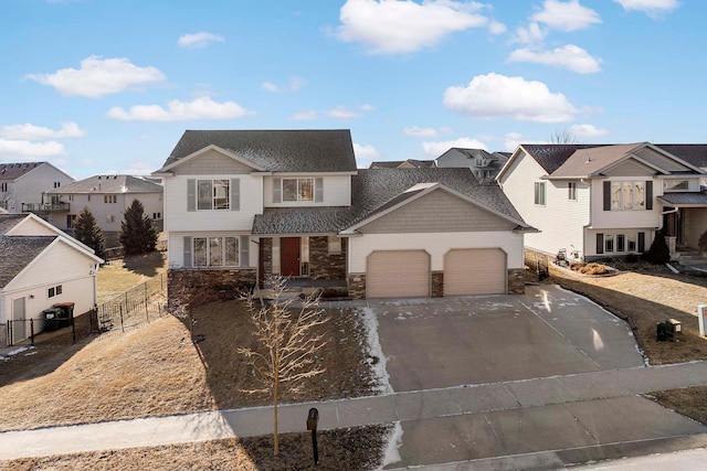 view of front of home featuring concrete driveway, an attached garage, fence, a residential view, and stone siding