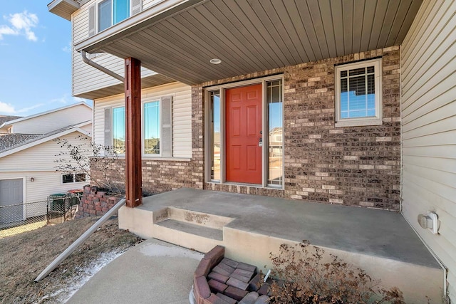 entrance to property featuring brick siding and fence