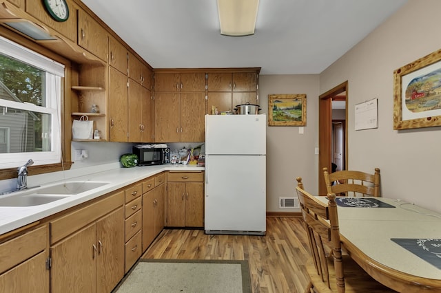 kitchen with sink, light wood-type flooring, and white fridge