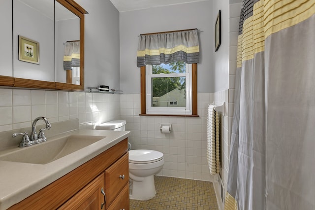 bathroom with tile walls, toilet, vanity, and tile patterned flooring