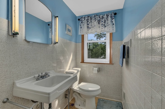 bathroom with sink, toilet, and tile walls