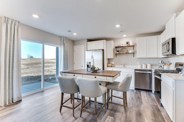 kitchen with stainless steel appliances, white cabinetry, a kitchen island, and sink