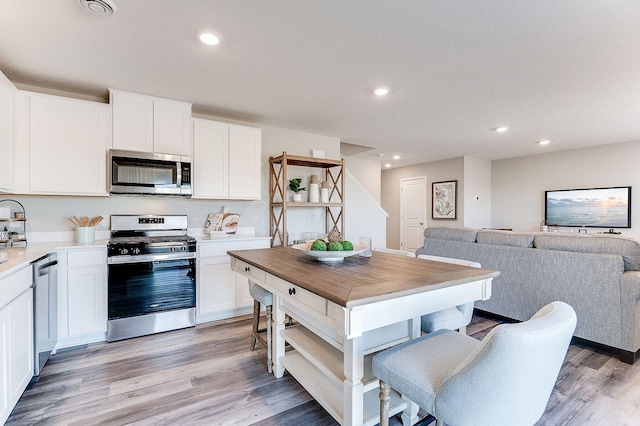 kitchen with stainless steel appliances, light hardwood / wood-style flooring, and white cabinetry