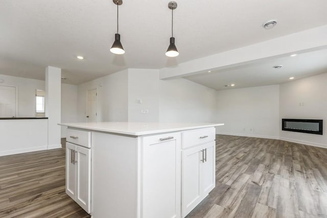 kitchen featuring white cabinets, a center island, light hardwood / wood-style floors, hanging light fixtures, and beam ceiling