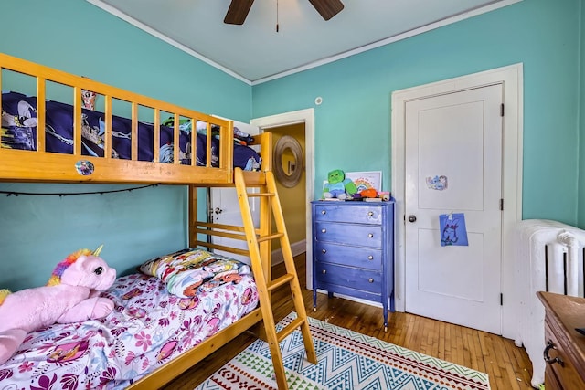 bedroom featuring hardwood / wood-style flooring, ornamental molding, radiator, and ceiling fan