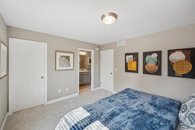 bedroom featuring ensuite bathroom and light carpet